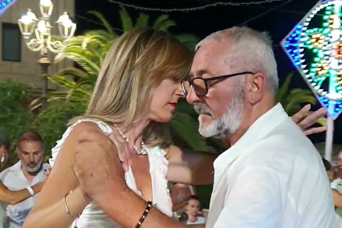 Una coppia in bianco balla abbracciata in piazza