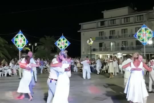 Coppie che ballano in piazza di notte